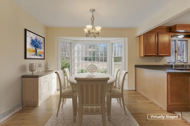 dining space with sink, light hardwood / wood-style flooring, and a notable chandelier