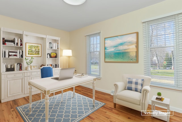 home office with built in shelves, light hardwood / wood-style flooring, and a healthy amount of sunlight