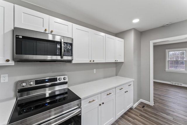 kitchen with white cabinets, stainless steel appliances, and dark wood-type flooring