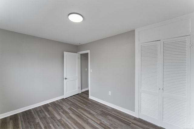 unfurnished bedroom with dark wood-type flooring and a closet