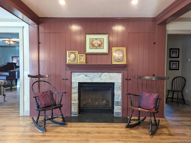 living area featuring hardwood / wood-style floors, ornamental molding, and wooden walls