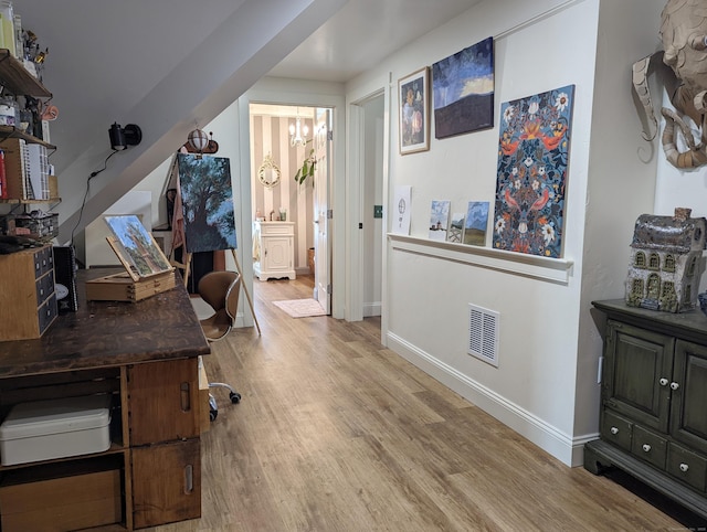 home office featuring light wood-type flooring and a notable chandelier