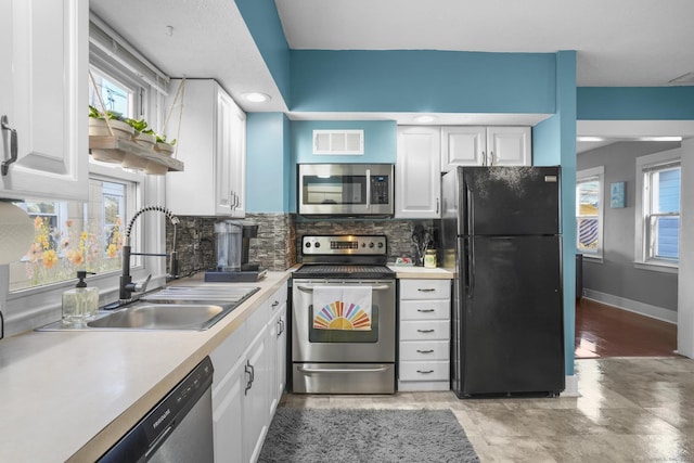 kitchen with decorative backsplash, white cabinetry, sink, and appliances with stainless steel finishes