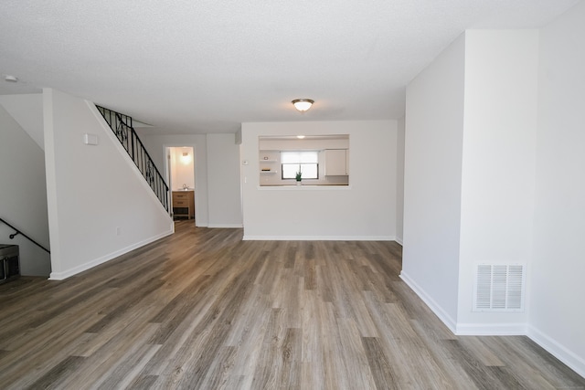 unfurnished living room featuring wood-type flooring and a textured ceiling