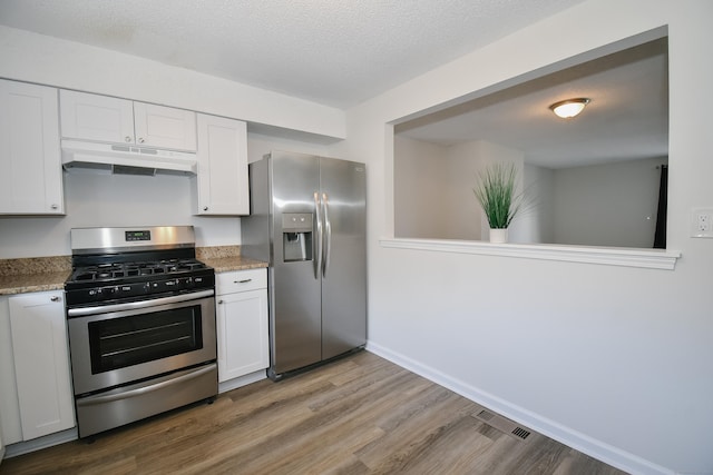 kitchen featuring hardwood / wood-style floors, white cabinets, stainless steel appliances, and a textured ceiling