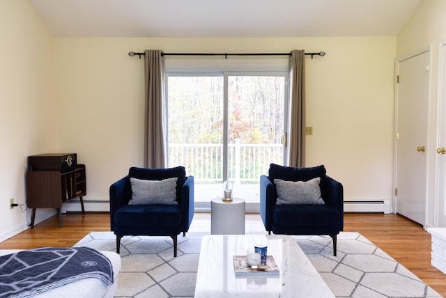 living area featuring plenty of natural light, a baseboard heating unit, and wood finished floors