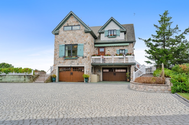 view of front of property featuring an attached garage, stone siding, stairs, and decorative driveway