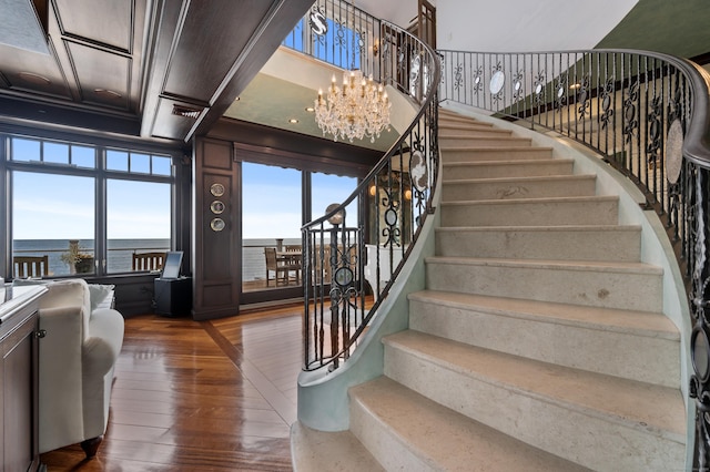 stairway featuring a chandelier, wood-type flooring, and coffered ceiling