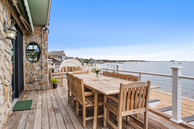 wooden terrace featuring a water view and outdoor dining space