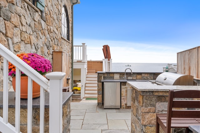 view of patio featuring area for grilling, a sink, a water view, stairway, and grilling area