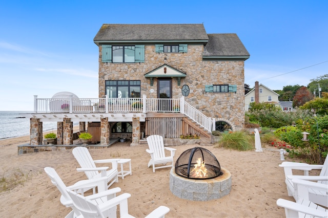 back of property with stairway, a fire pit, a deck with water view, and a patio