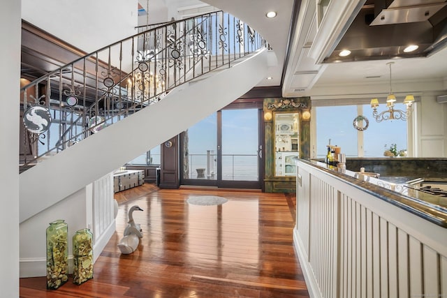 interior space featuring a towering ceiling, stairway, wood finished floors, ventilation hood, and a notable chandelier