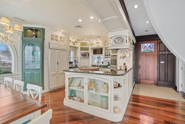 kitchen with a chandelier, hardwood / wood-style flooring, stainless steel microwave, and open shelves