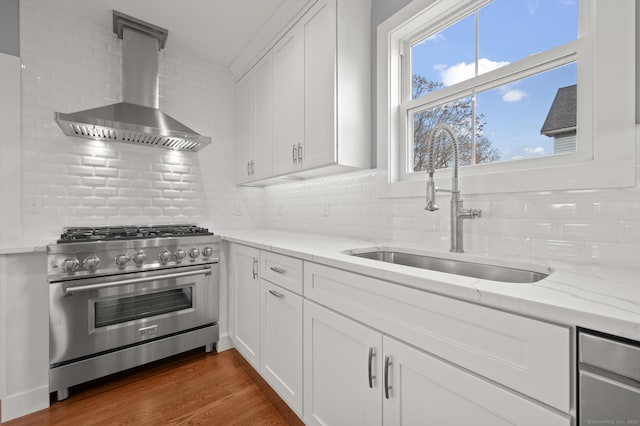 kitchen with stainless steel range, white cabinets, wall chimney range hood, and sink