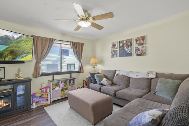 living room featuring dark wood-type flooring, baseboard heating, and ceiling fan