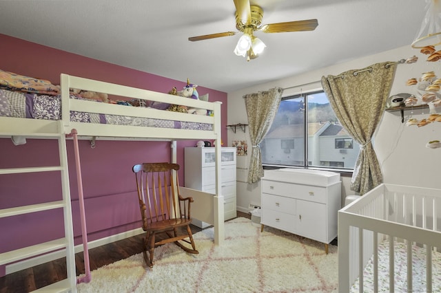 bedroom with ceiling fan and a nursery area