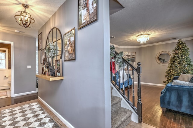 entryway featuring hardwood / wood-style flooring, a notable chandelier, ornamental molding, and a textured ceiling