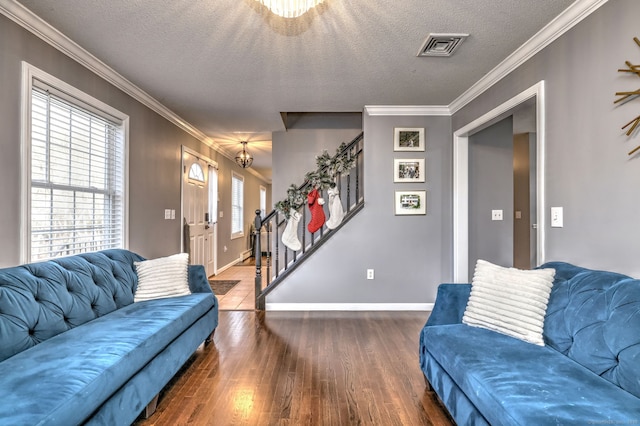 living room featuring a textured ceiling, dark wood-type flooring, an inviting chandelier, and ornamental molding