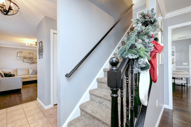 staircase featuring tile patterned flooring, a textured ceiling, a chandelier, and ornamental molding