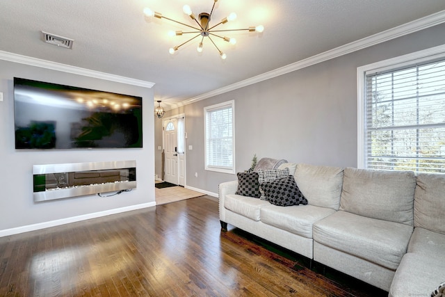 living room with hardwood / wood-style floors, crown molding, a textured ceiling, a fireplace, and a chandelier