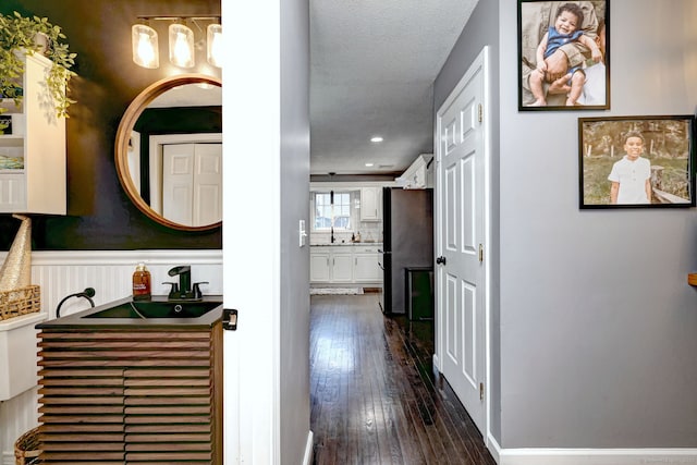 corridor with a textured ceiling and dark wood-type flooring