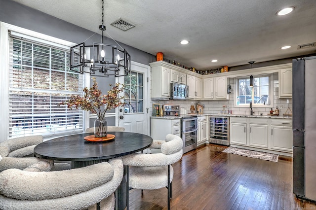 kitchen with white cabinetry, sink, beverage cooler, stainless steel appliances, and decorative backsplash