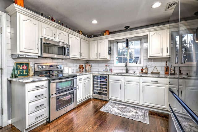 kitchen with white cabinetry, sink, wine cooler, decorative light fixtures, and appliances with stainless steel finishes