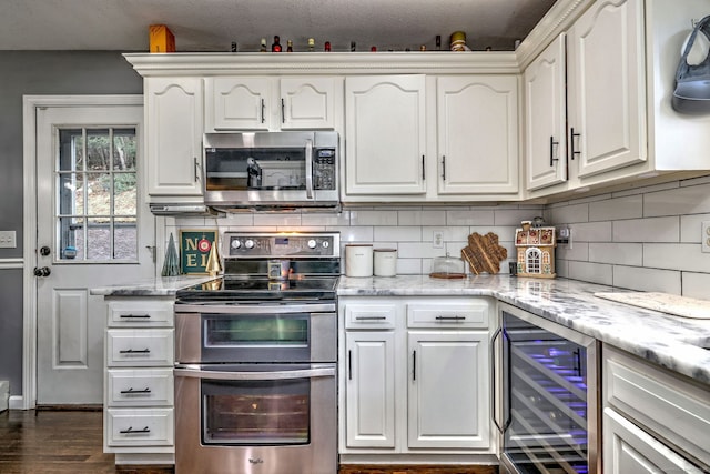 kitchen featuring wine cooler, light stone counters, backsplash, white cabinets, and appliances with stainless steel finishes