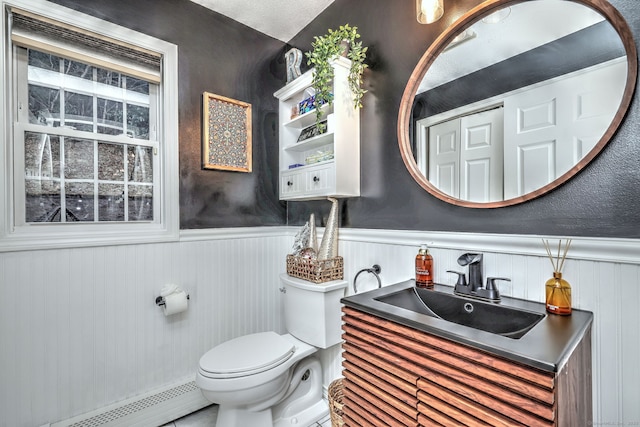 bathroom with a textured ceiling, vanity, a baseboard radiator, and toilet