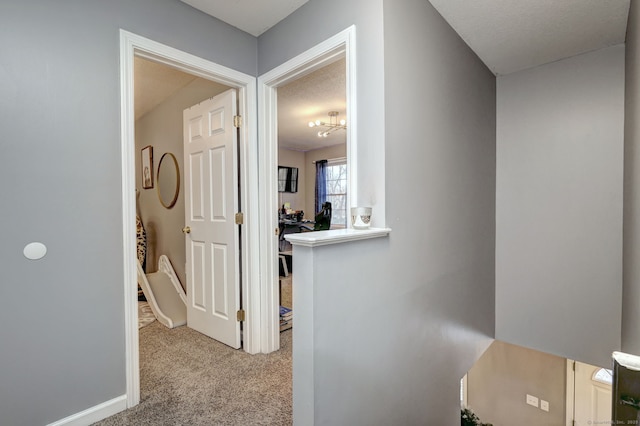 hallway featuring light carpet and a textured ceiling