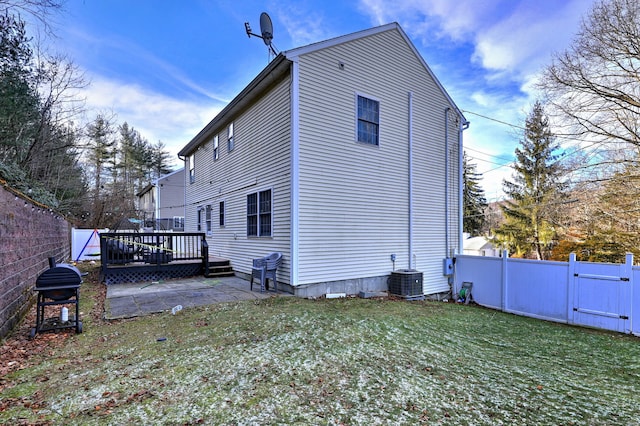 back of property with a deck, central AC unit, a patio area, and a lawn