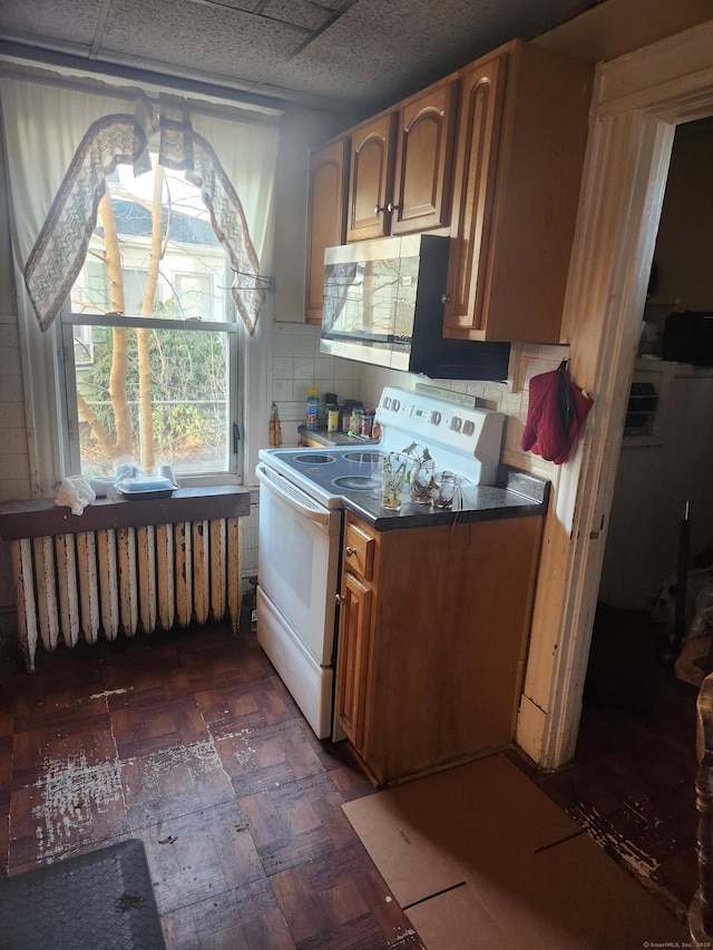 kitchen featuring white electric range oven, backsplash, and radiator