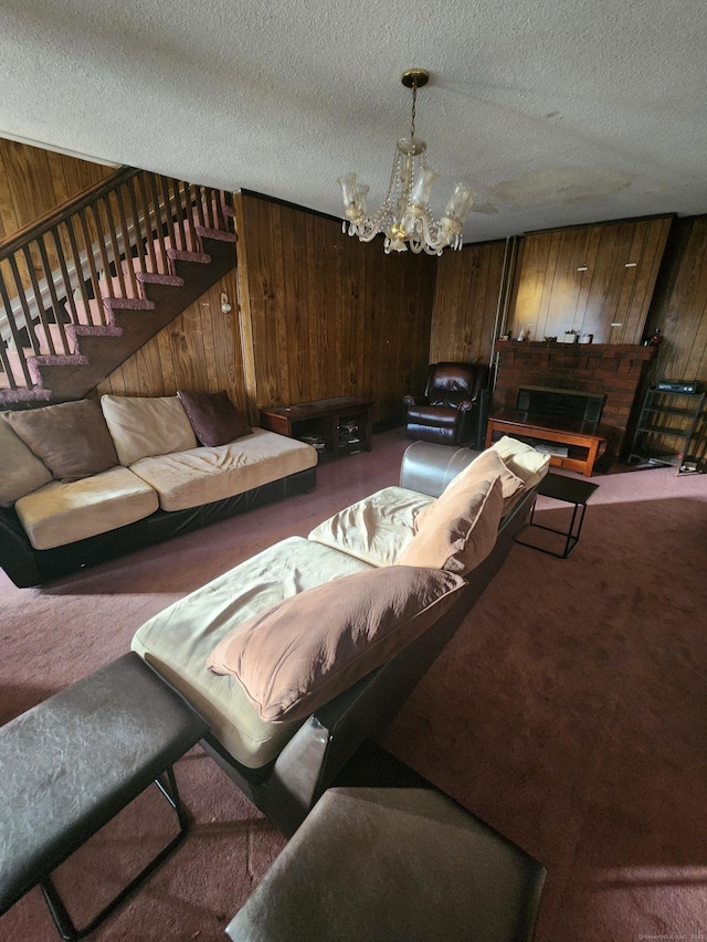 living room featuring carpet flooring, a notable chandelier, wood walls, and a textured ceiling