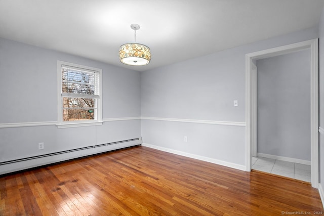 unfurnished room with wood-type flooring and baseboard heating