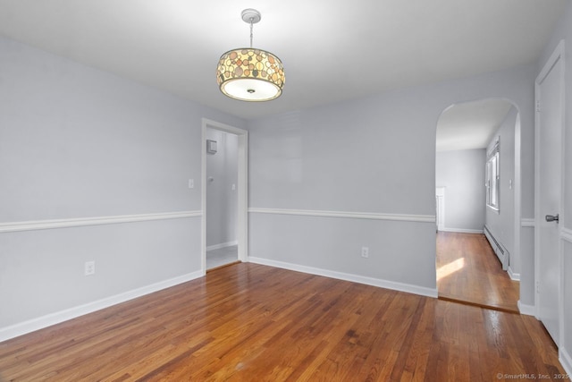 unfurnished room with wood-type flooring and a baseboard heating unit