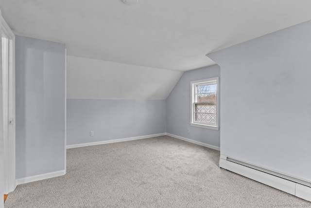 additional living space with light carpet, vaulted ceiling, and a baseboard heating unit