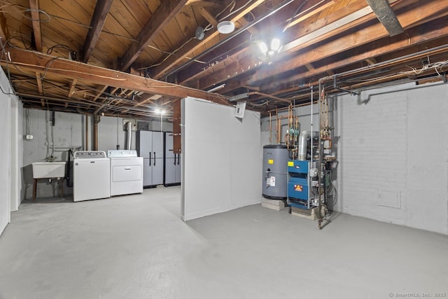 basement featuring separate washer and dryer, sink, and water heater