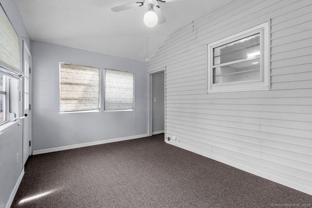 unfurnished room with plenty of natural light, ceiling fan, lofted ceiling, and dark carpet