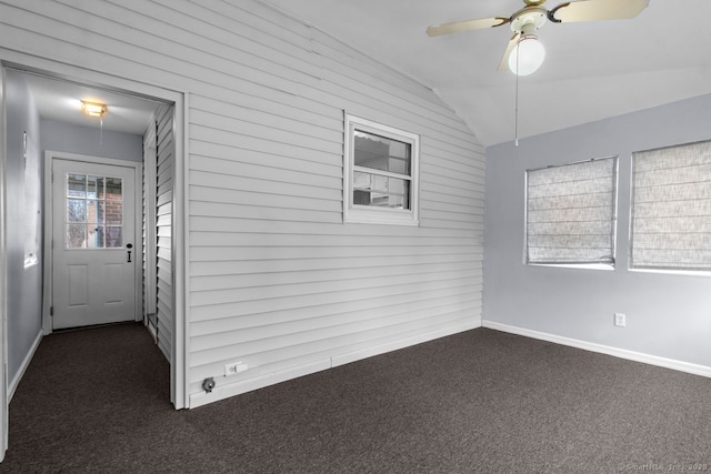 carpeted spare room featuring ceiling fan, lofted ceiling, and wooden walls