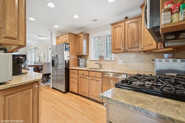 kitchen featuring sink, backsplash, ornamental molding, stainless steel appliances, and light hardwood / wood-style flooring