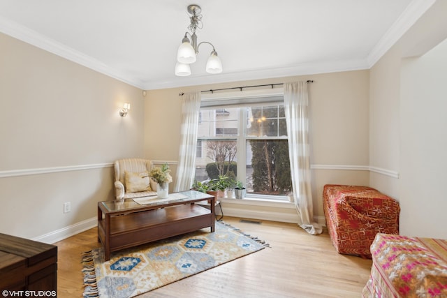 sitting room with ornamental molding, an inviting chandelier, and light wood-type flooring