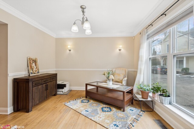 living area featuring ornamental molding, light hardwood / wood-style floors, and a notable chandelier