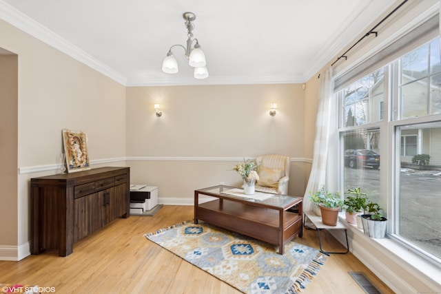 sitting room with crown molding, a chandelier, and light wood-type flooring