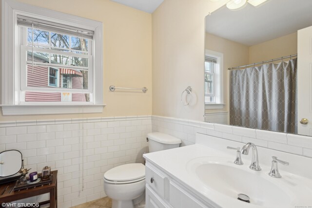 bathroom with vanity, toilet, and tile walls