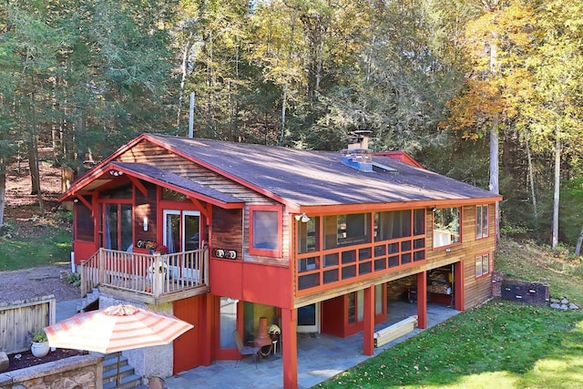 view of front of home with a front yard, a patio area, and a sunroom