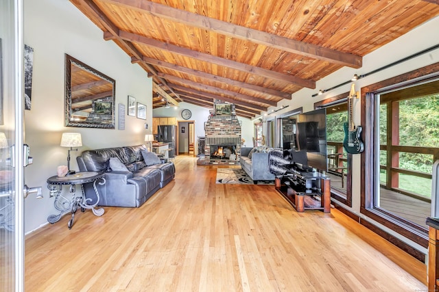 living room with lofted ceiling with beams, a fireplace, light hardwood / wood-style floors, and wooden ceiling