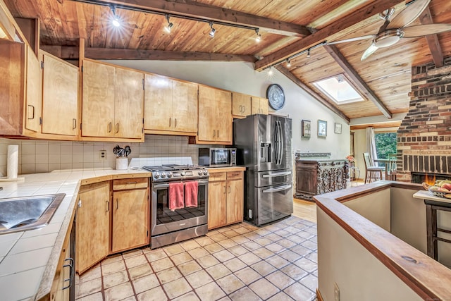 kitchen with ceiling fan, tile counters, rail lighting, stainless steel appliances, and backsplash