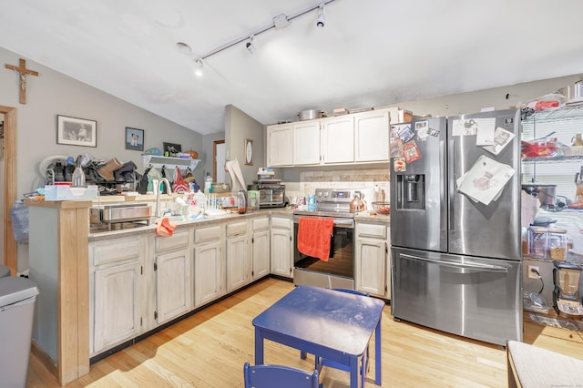 kitchen with decorative backsplash, stainless steel appliances, vaulted ceiling, and light hardwood / wood-style floors