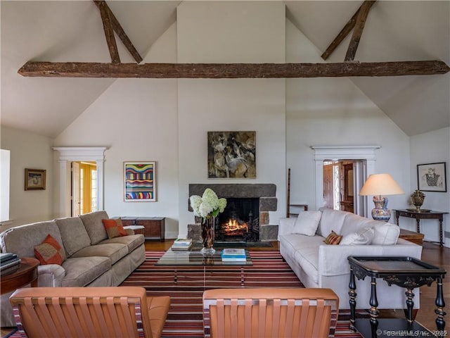 living room featuring beamed ceiling, wood-type flooring, a premium fireplace, and a wealth of natural light