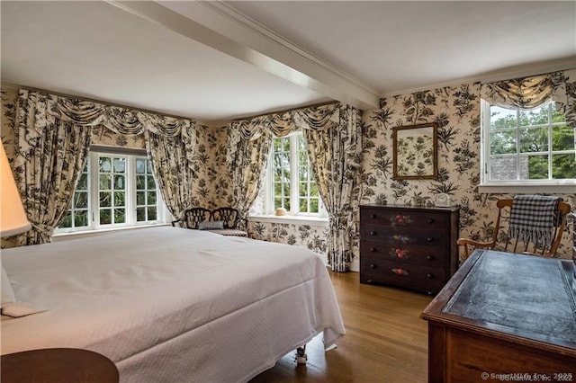 bedroom with beam ceiling, crown molding, and wood-type flooring